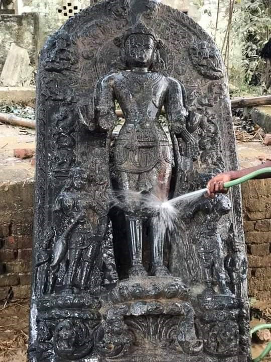 खुदाई में मिली प्राचीन मूर्ति की सफाई करते लोग।
